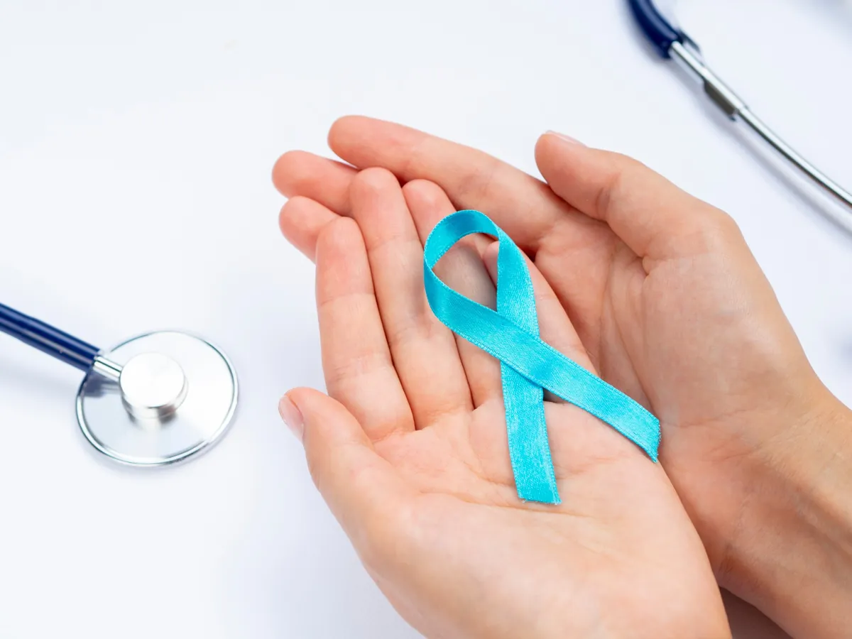 Manos sosteniendo un listón azul de la lucha contra el cáncer de próstata junto a un estetoscopio
